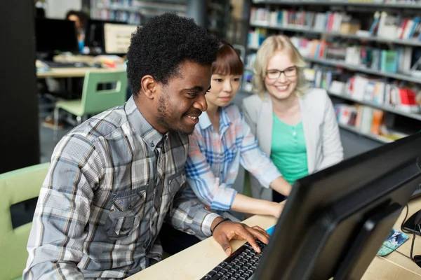 Estudantes internacionais com computadores na biblioteca — Fotografia de Stock