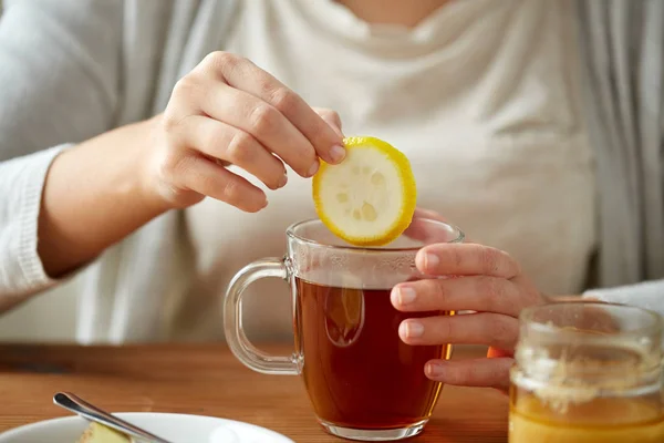 Menutup wanita menambahkan lemon ke teh dengan madu — Stok Foto