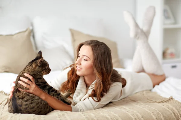 Gelukkig jonge vrouw met kat liggend in bed thuis — Stockfoto