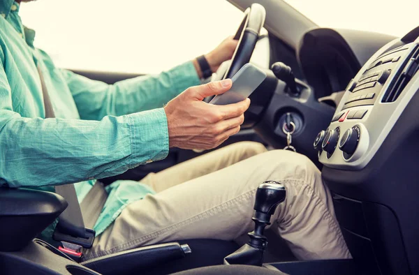 Close up of man with smartphone driving car — Stock Photo, Image