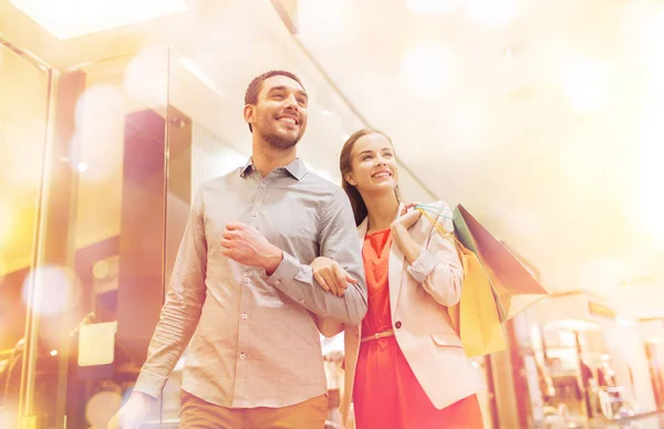 Feliz jovem casal com sacos de compras no shopping — Fotografia de Stock