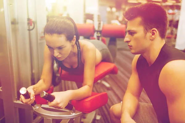 Mujer joven con entrenador haciendo ejercicio en la máquina de gimnasio —  Fotos de Stock