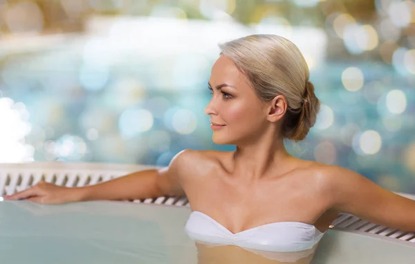 Mujer feliz sentada en el jacuzzi junto a la piscina — Foto de Stock