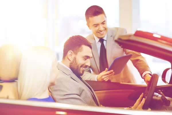 Casal feliz com revendedor de carro em auto show ou salão — Fotografia de Stock