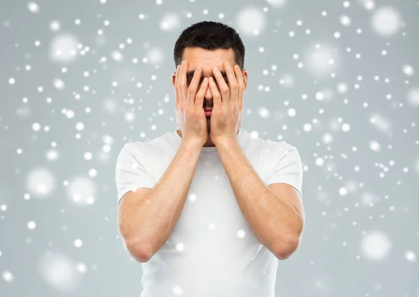 Человек, закрывающий лицо руками от снега — стоковое фото
