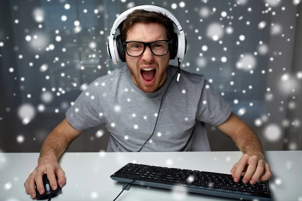 Homme dans casque jouant jeu vidéo d'ordinateur à la maison — Photo