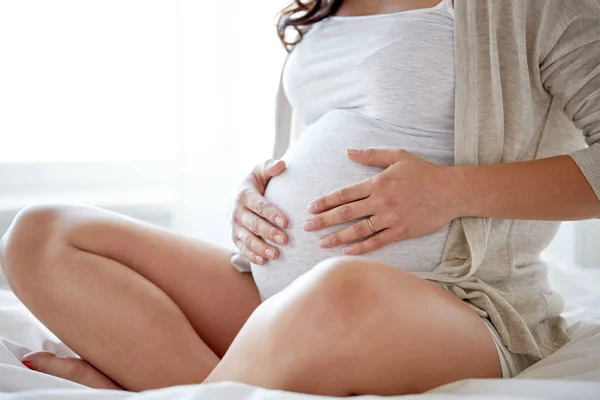 Kobieta w ciąży, siedząc na łóżku w domu z bliska — Zdjęcie stockowe