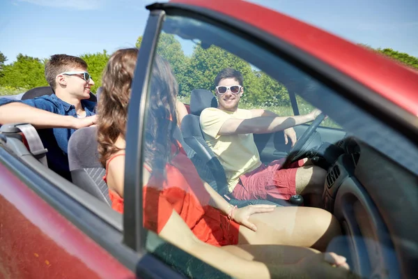 Happy friends driving in cabriolet car and talking — Stock Photo, Image