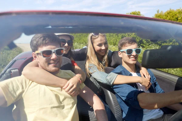 Amigos felizes dirigindo em carro cabriolet ao ar livre — Fotografia de Stock