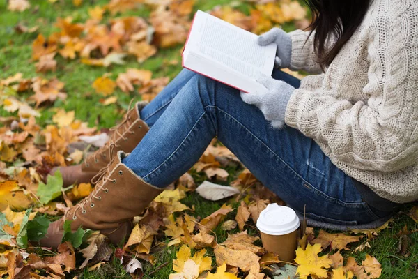 Frau mit Buch trinkt Kaffee im Herbstpark — Stockfoto