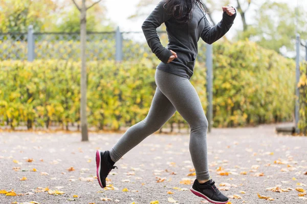 Close up of young woman running in autumn park — Stock Photo, Image