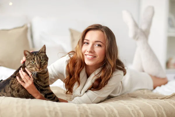 Glad ung kvinna med katt i sängen hemma — Stockfoto