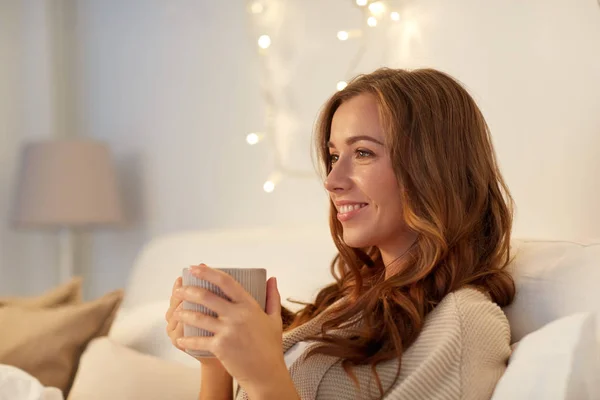 Gelukkige vrouw met kopje koffie in bed thuis — Stockfoto