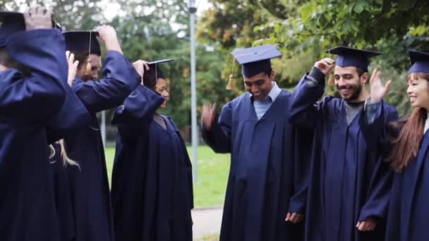 Estudiantes felices lanzando tablas de mortero — Vídeos de Stock