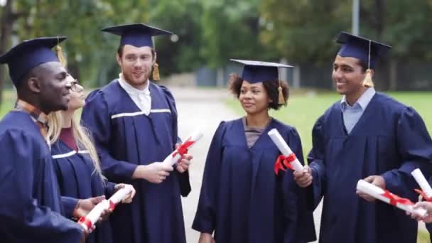 Estudiantes felices en morteros con diplomas — Vídeo de stock