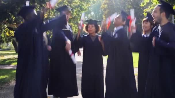 Estudantes felizes em placas de argamassa com diplomas — Vídeo de Stock