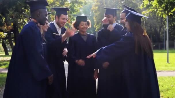 Щасливі студенти в мінометних дошках з руками зверху — стокове відео