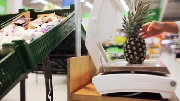 Kvinna som väger ananas på skalan vid livsmedelsbutik — Stockvideo