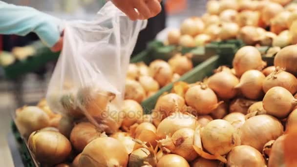 Mujer poniendo cebolla a la bolsa en la tienda de comestibles — Vídeos de Stock