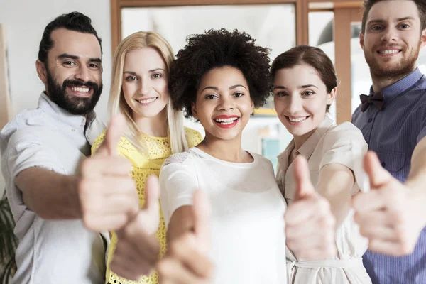 Equipo creativo feliz mostrando pulgares hacia arriba en la oficina — Foto de Stock