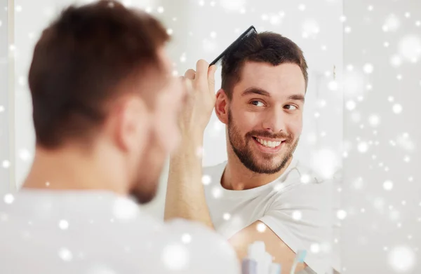 Hombre feliz cepillado pelo con peine en el baño — Foto de Stock