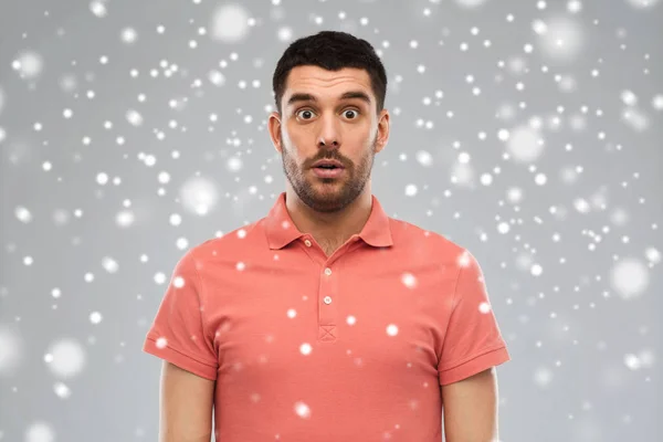 Здивований чоловік у футболці поло над сніговим тлом — стокове фото