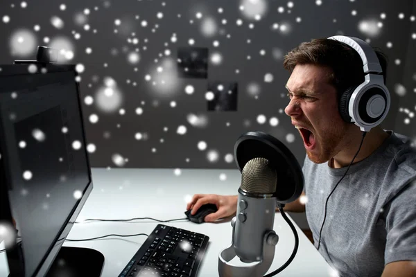 Hombre en auriculares jugando videojuego de ordenador en casa —  Fotos de Stock