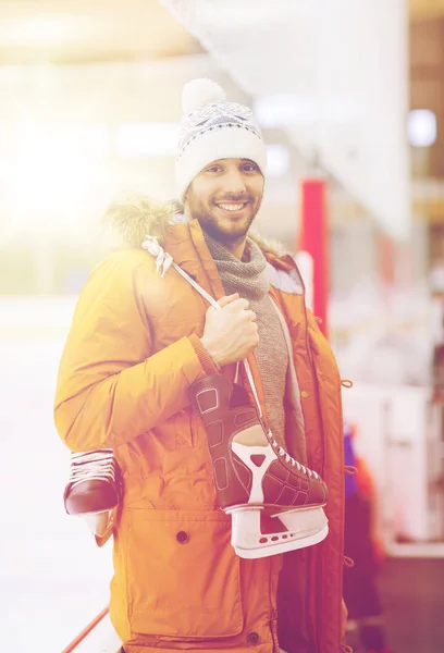 Heureux jeune homme avec patins à glace sur patinoire — Photo