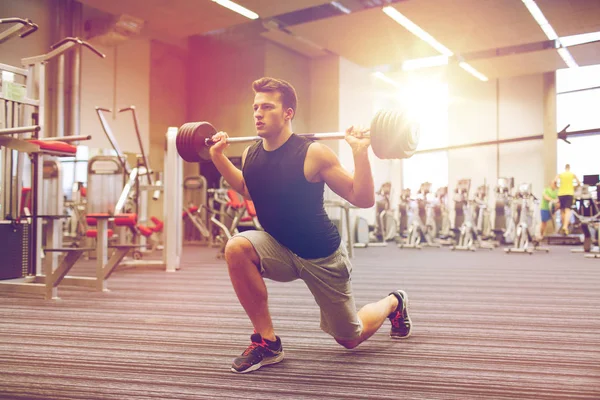 Young man flexing muscles with barbell in gym — Stock Photo, Image