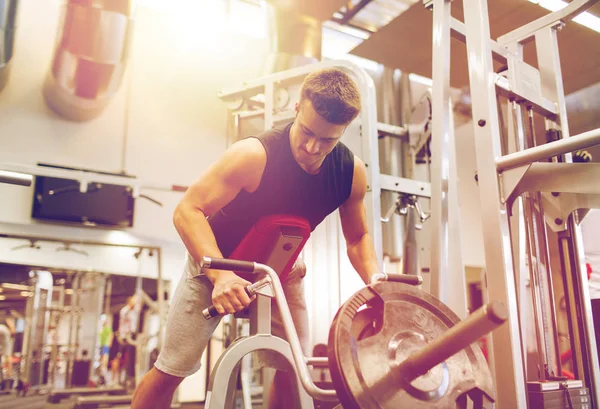 Joven hombre haciendo ejercicio en t-bar fila máquina en el gimnasio — Foto de Stock