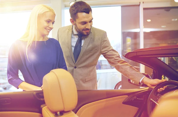 Happy couple buying car in auto show or salon — Stock Photo, Image