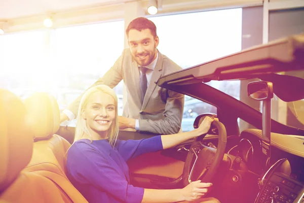Šťastný pár koupit auto v autosalonu nebo salónek — Stock fotografie