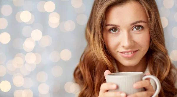 Close up de mulher feliz com xícara de chá sobre luzes — Fotografia de Stock