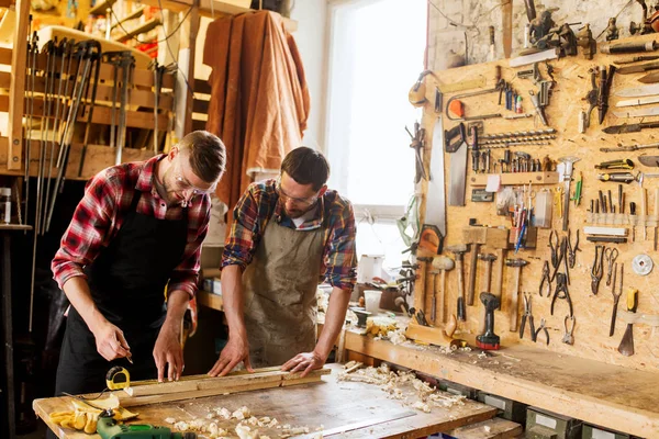 Плотники с линейкой и деревянной доской в мастерской — стоковое фото