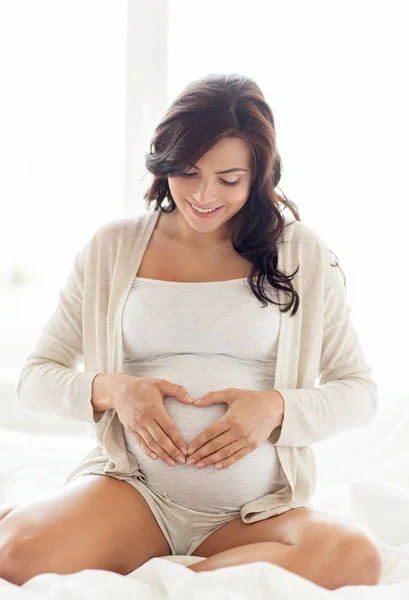 Gelukkig zwangere vrouw hart gebaar thuis — Stockfoto