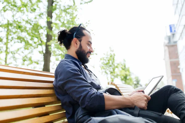 Uomo con tablet pc seduto sulla panchina della città — Foto Stock