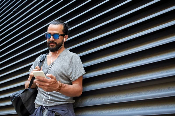 Man with earphones and smartphone on city street — Stock Photo, Image