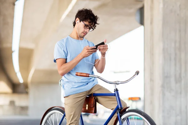 Mann mit Smartphone und Kopfhörer auf Fahrrad — Stockfoto