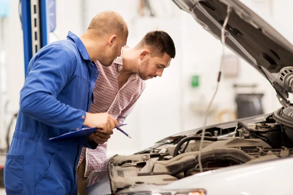 Automechaniker mit Klemmbrett und Mann im Autohaus — Stockfoto