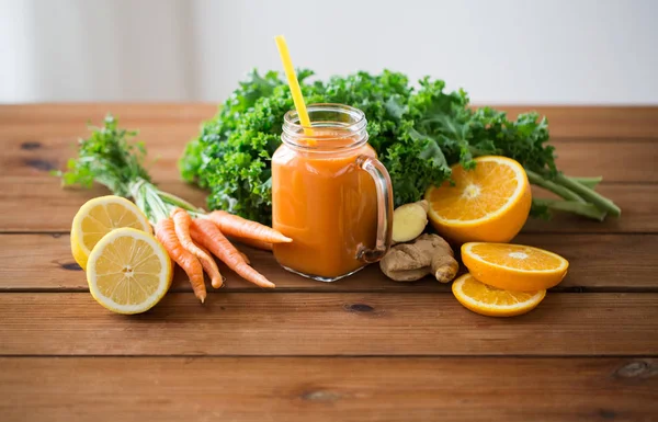 Glass jug of carrot juice, fruits and vegetables — Stock Photo, Image
