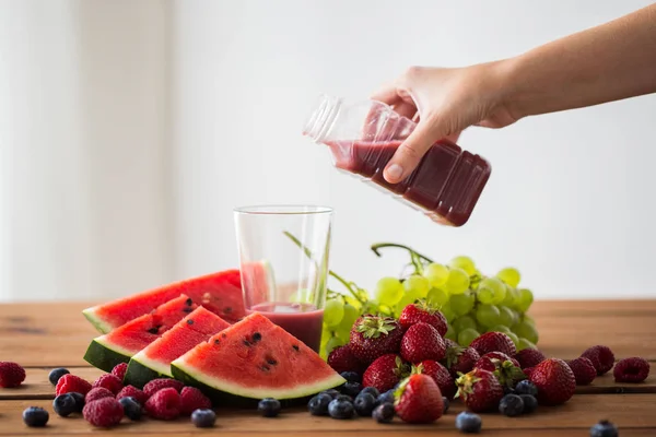Ручной разлив фруктового сока из бутылки в стекло — стоковое фото