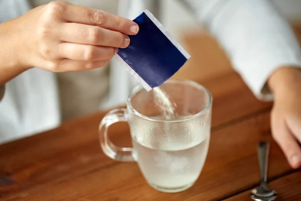 Kvinna som häller medicinering i kopp vatten — Stockfoto