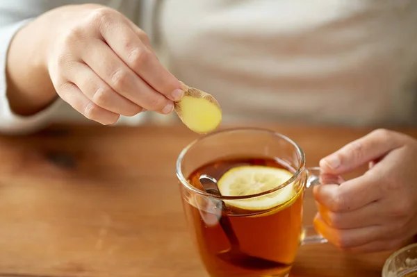 Primer plano de la mujer añadiendo jengibre al té con limón —  Fotos de Stock