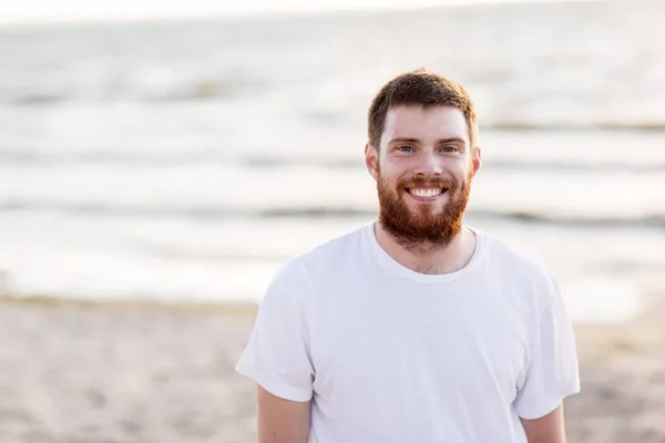 Mutlu gülümseyen genç adam sahilde kırmızı sakallı — Stok fotoğraf