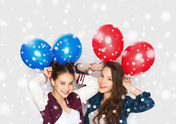 Счастливые девочки-подростки с гелиевыми шариками над снегом — стоковое фото
