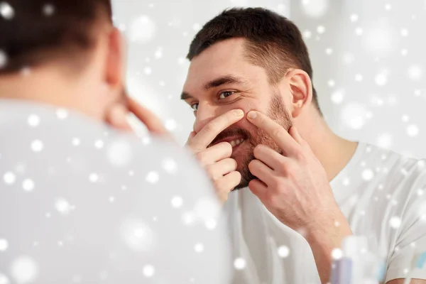 Uomo sorridente che stringe brufolo allo specchio del bagno — Foto Stock