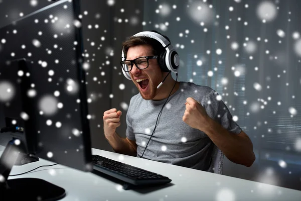 Hombre en auriculares jugando videojuego de ordenador en casa —  Fotos de Stock