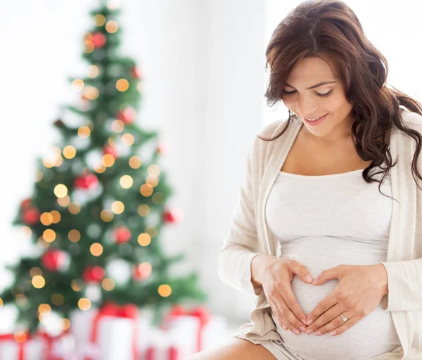 Happy pregnant woman making heart gesture at home — Stock Photo, Image