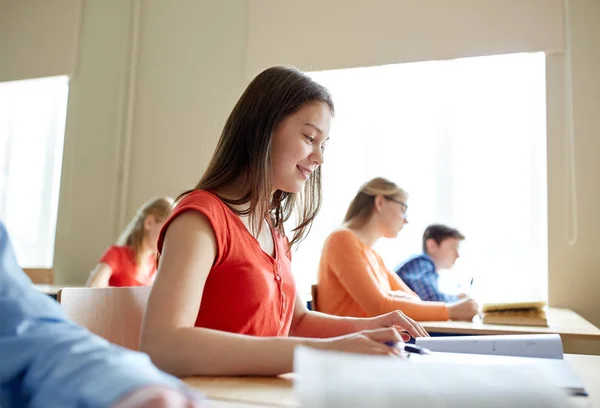 Nöjd student tjej med bok skriver skolan test — Stockfoto