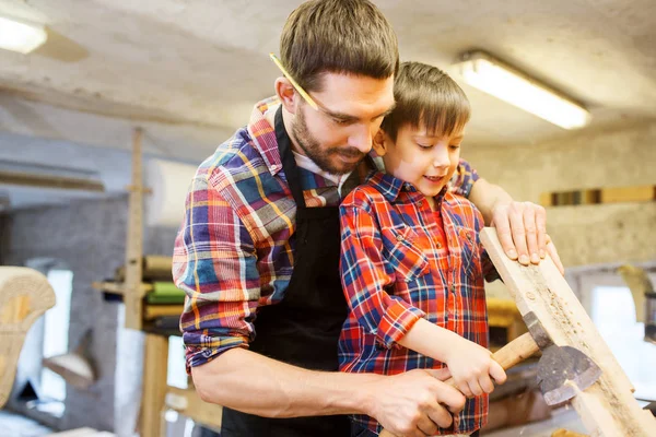 Padre e hijo con hacha y tabla de madera en el taller —  Fotos de Stock